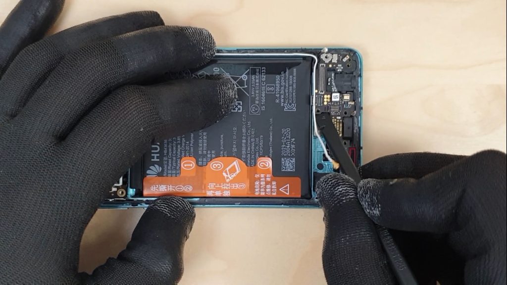 pour changer l'écran d'un Huawei P30 le technicien enlève la carte avec le connecteur de charge